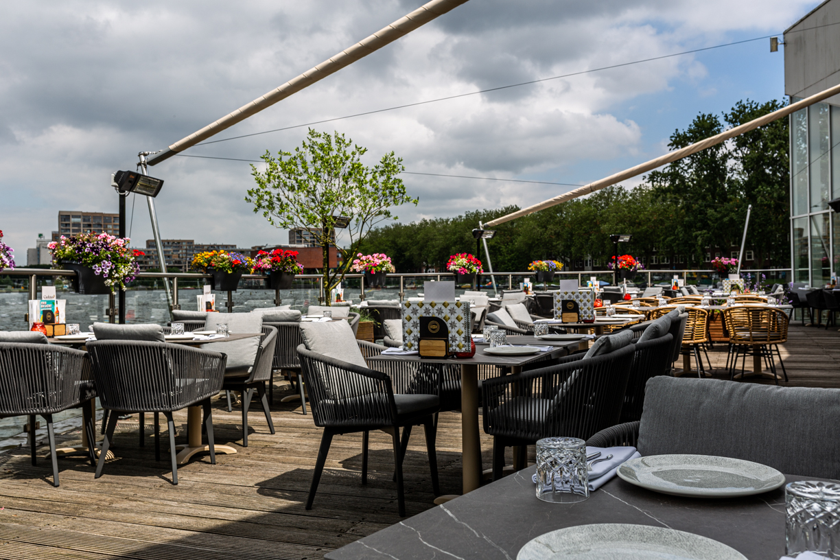 Terras met tafels en bloemen aan het water