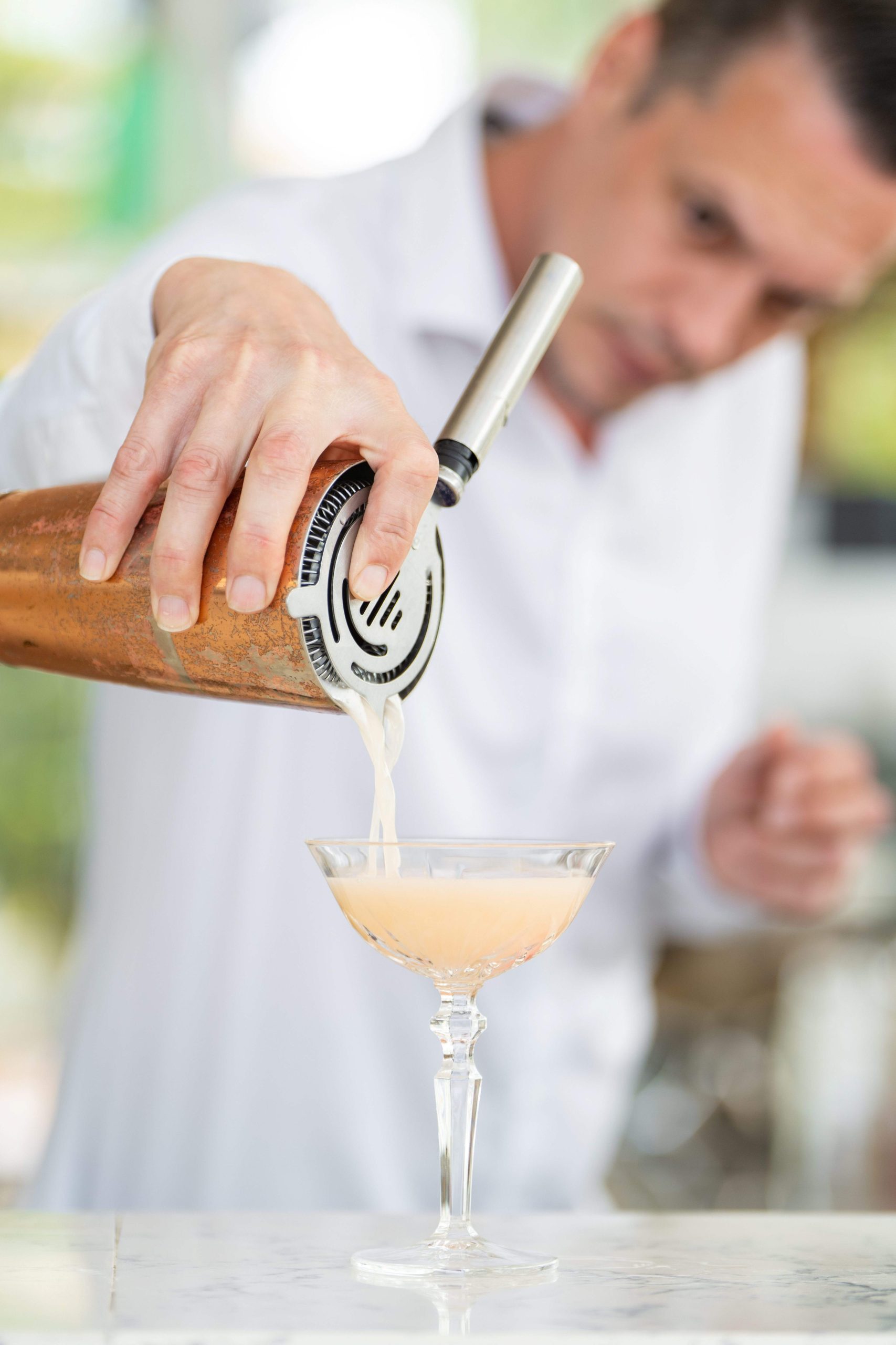 Bartender schenkt een cocktail in een coupe