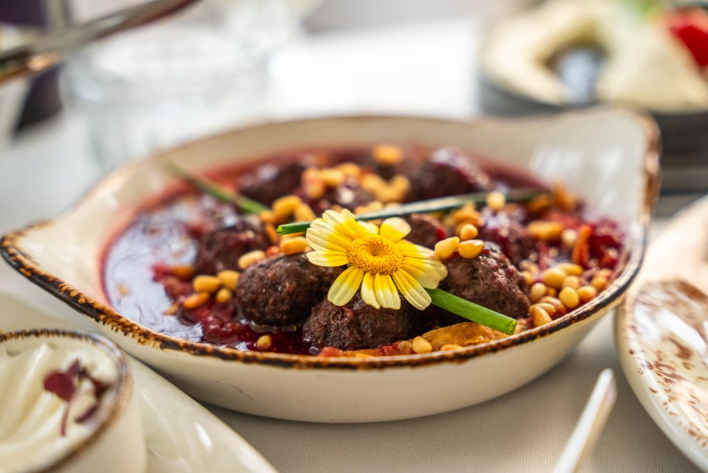 Gehaktballetjes in tomatensaus met pijnboompitten en een eetbare bloem
