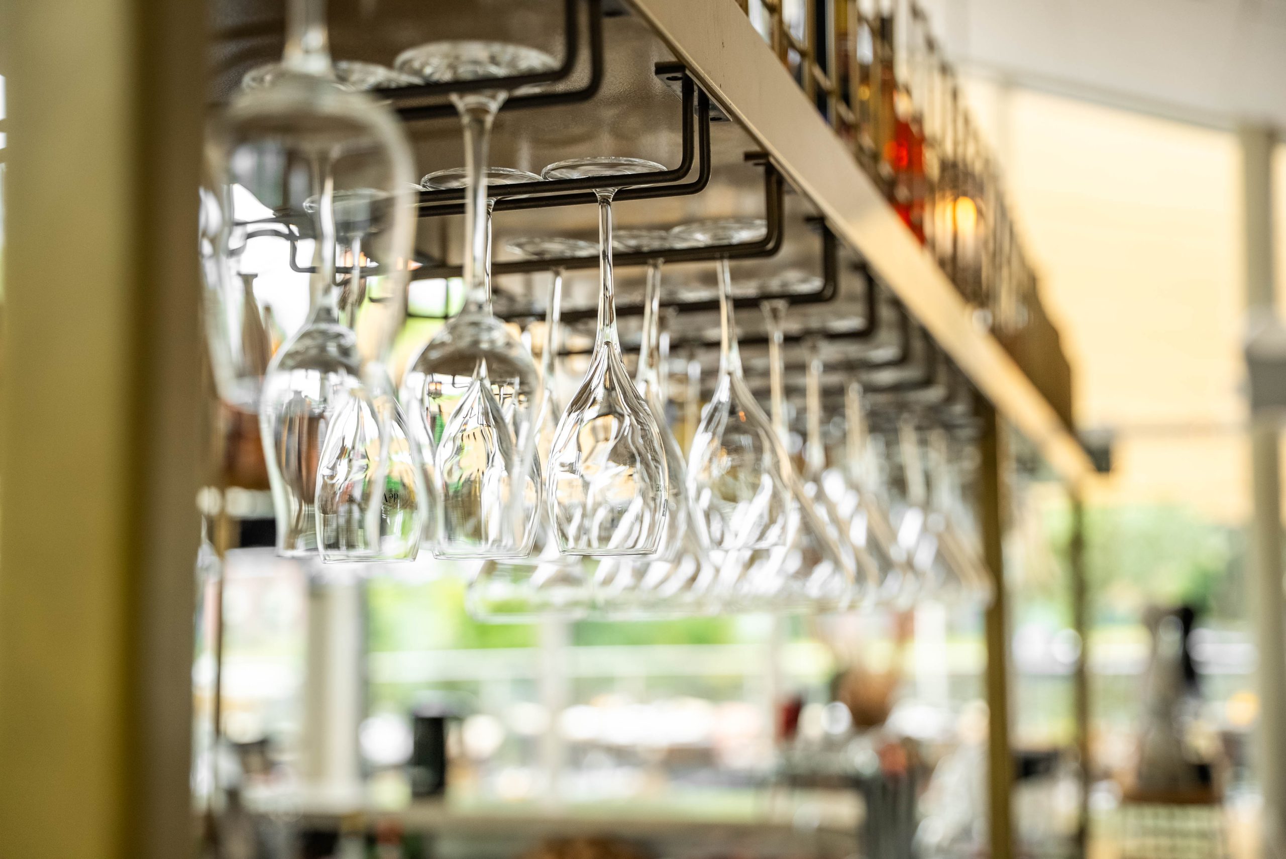 Rij wijnglazen boven de bar van Restaurant Cedars