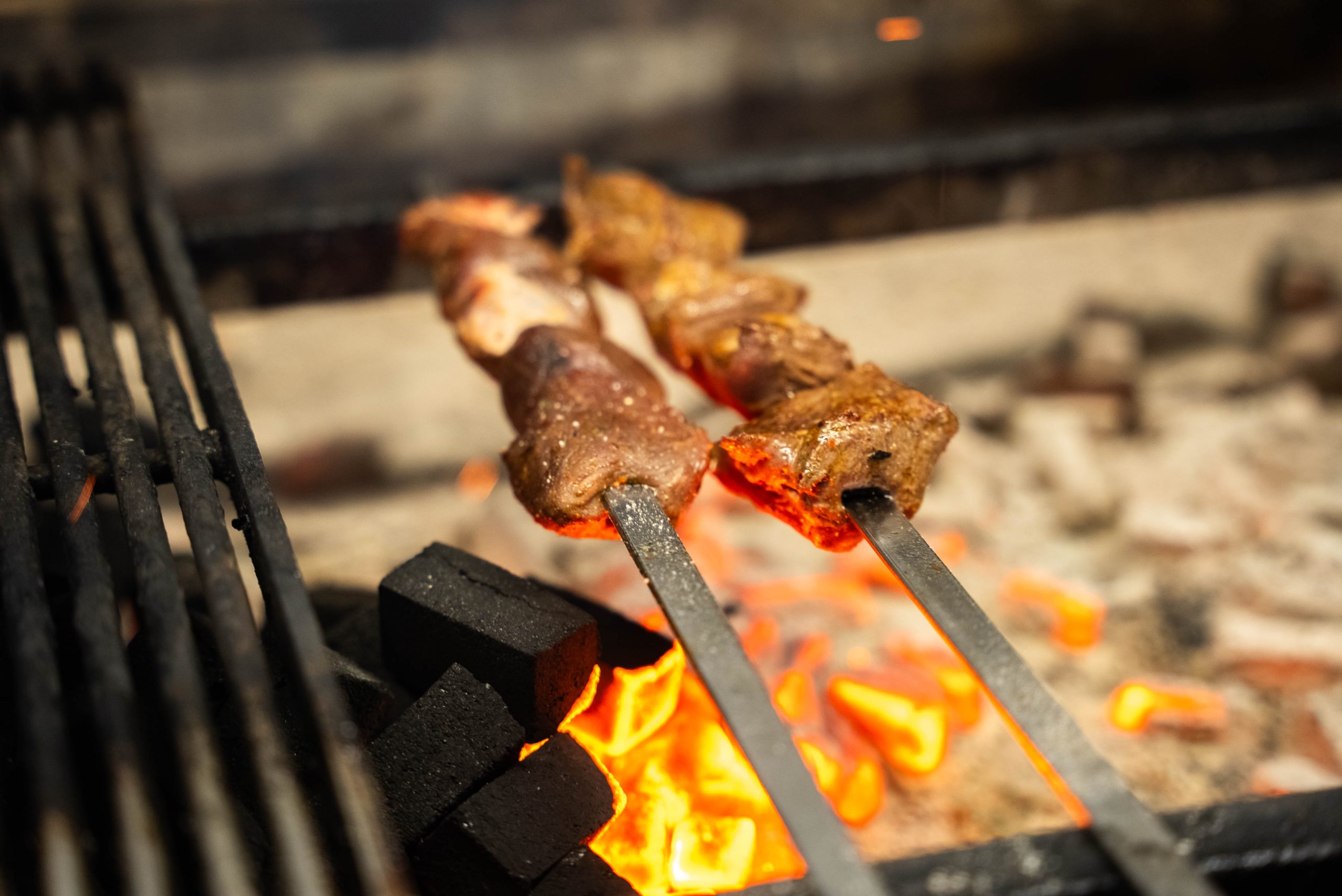Vleesspiesen boven de gloeiende houtskoolgrill van Cedars