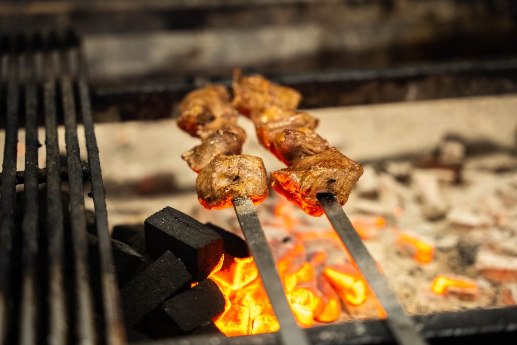 Kok grilt vleesspiesen boven de open houtskoolgrill van Cedars