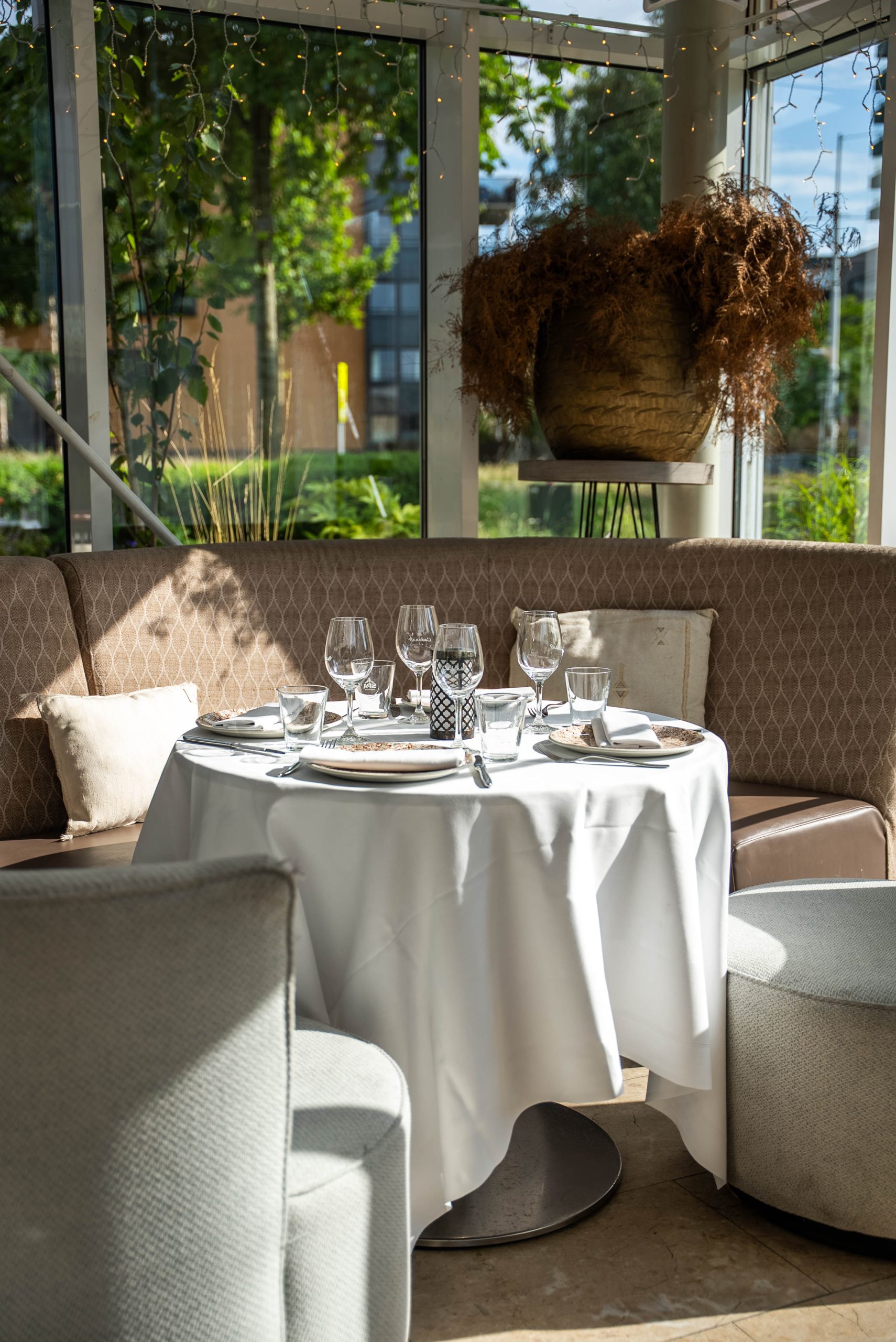Wit gedekte ronde tafels in de lichte serre van Restaurant Cedars